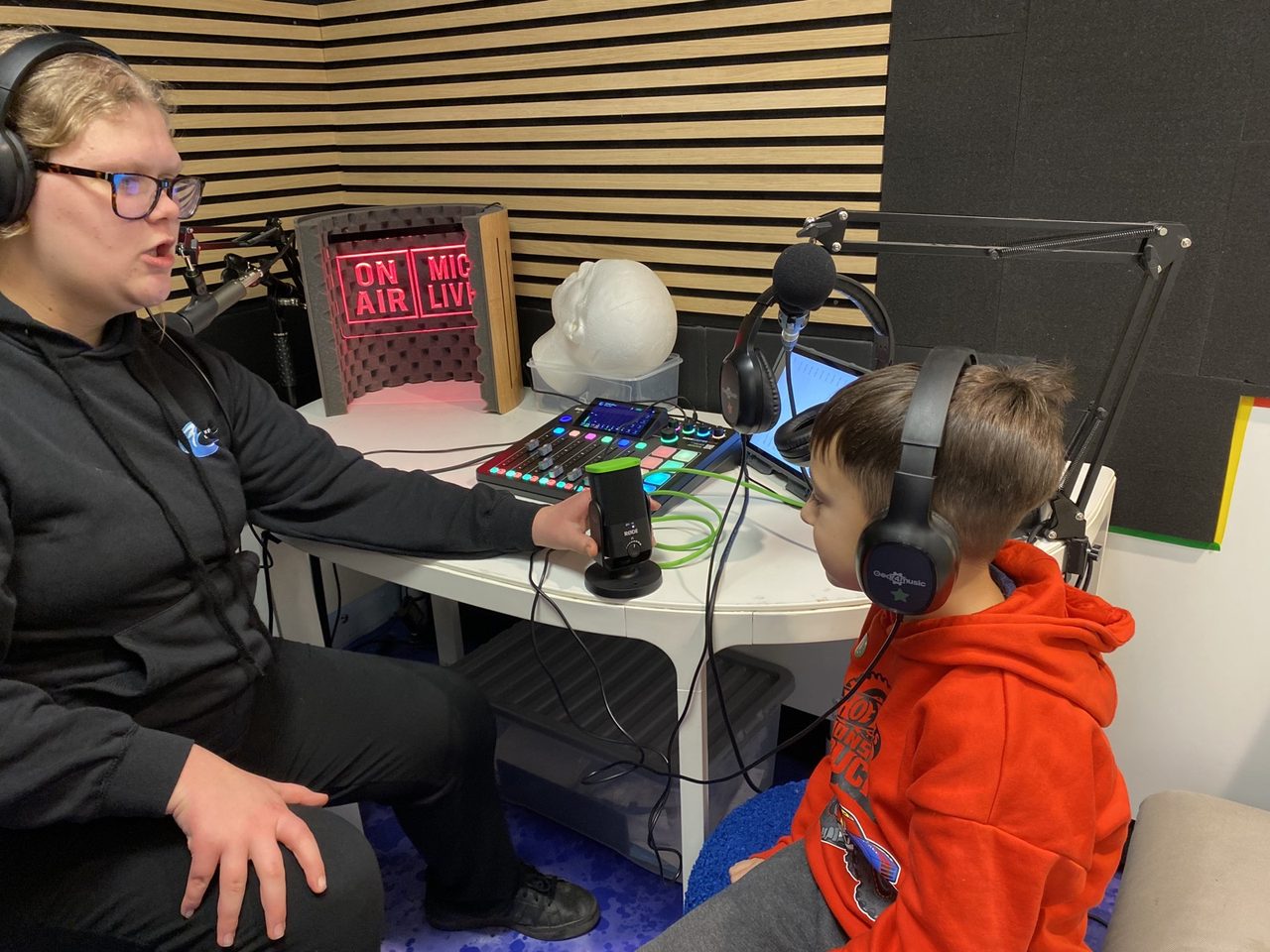 A workshop leader recording with a young participant in the radio studio