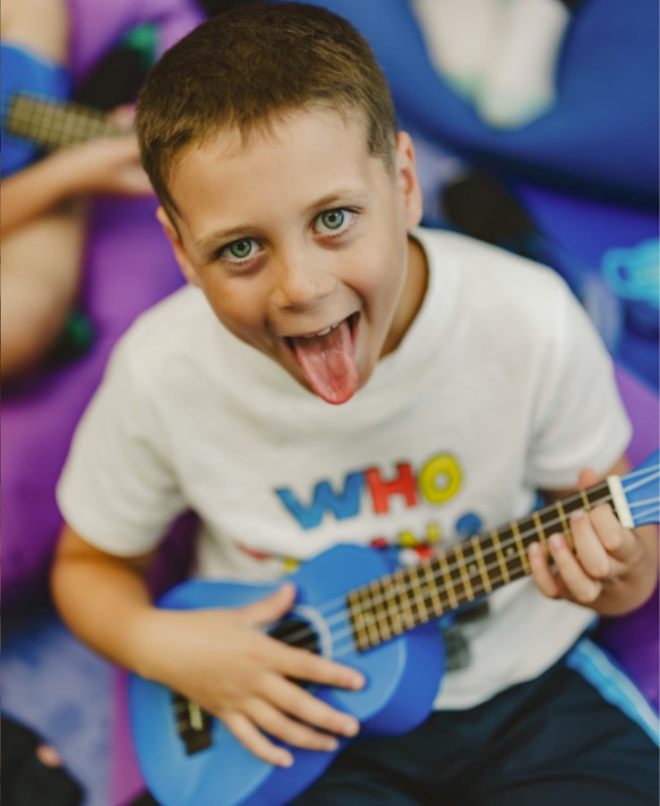 Boy playing a blue ukulele